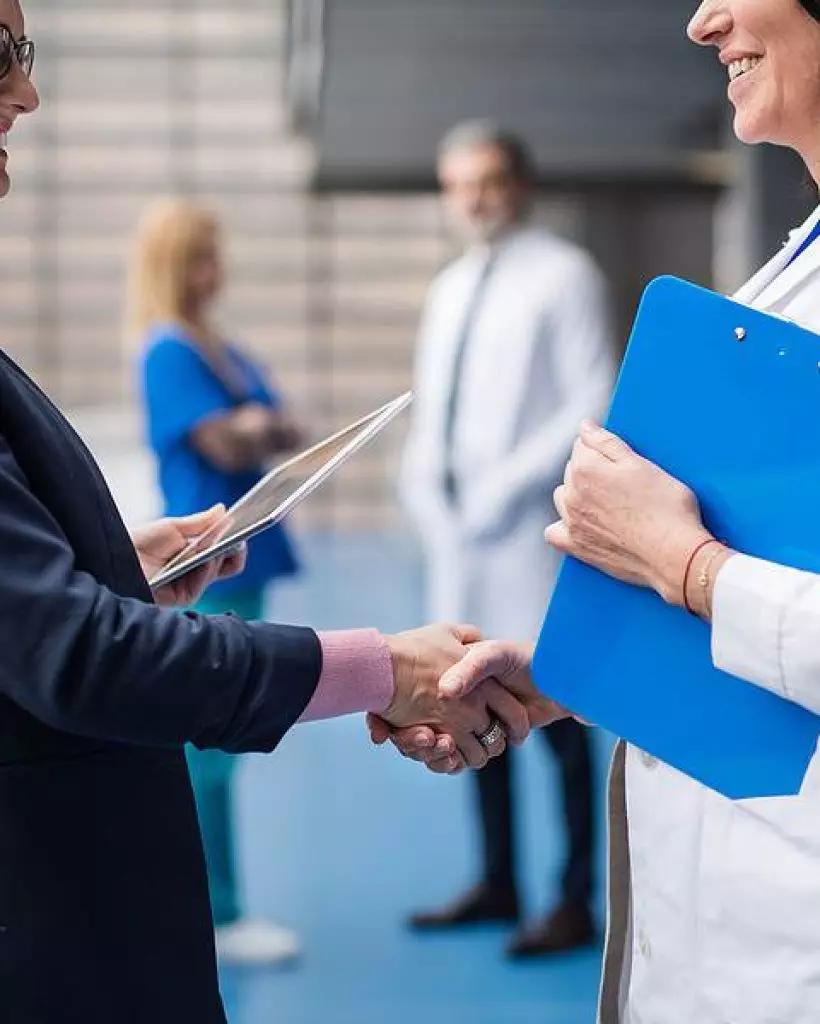 Doctor talking to pharmaceutical sales representative, shaking hands.